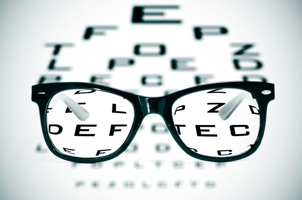 11325859 - eyeglasses over a blurry eye chart